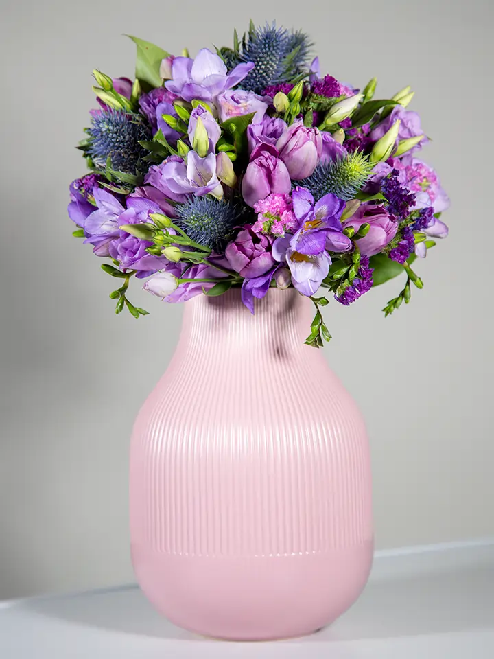 Bouquet viola di tulipani freesie eryngium in vaso rosa